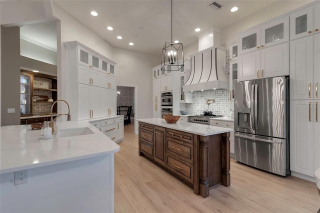 kitchen featuring visible vents, premium range hood, a sink, stainless steel appliances, and a center island