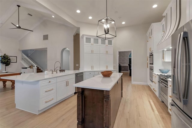 kitchen featuring light wood-type flooring, a sink, a kitchen island, stainless steel appliances, and light countertops