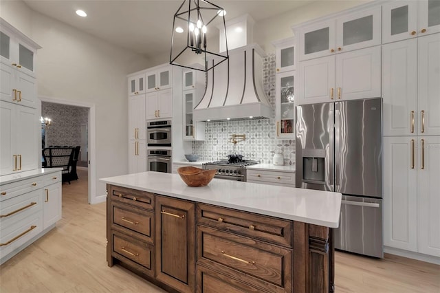 kitchen with backsplash, light wood-type flooring, appliances with stainless steel finishes, custom exhaust hood, and white cabinetry