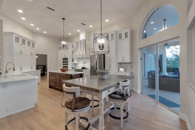 kitchen featuring visible vents, a sink, appliances with stainless steel finishes, white cabinetry, and light wood-type flooring