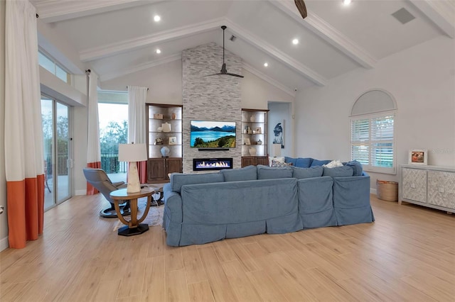 living room with wood finished floors, visible vents, high vaulted ceiling, beam ceiling, and a stone fireplace