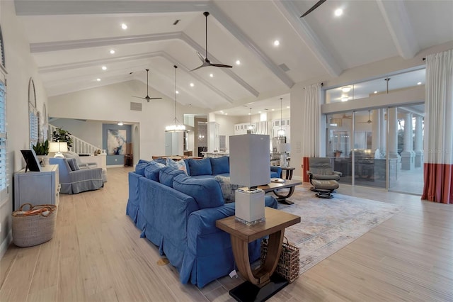 living area with stairs, beam ceiling, light wood-style flooring, high vaulted ceiling, and a ceiling fan