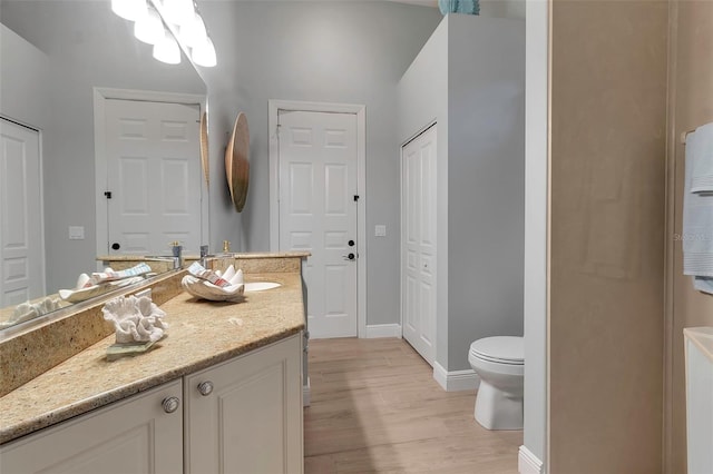 full bathroom with toilet, vanity, baseboards, and wood finished floors