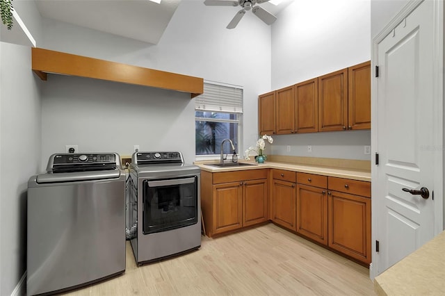 washroom with independent washer and dryer, a high ceiling, cabinet space, a sink, and light wood-type flooring