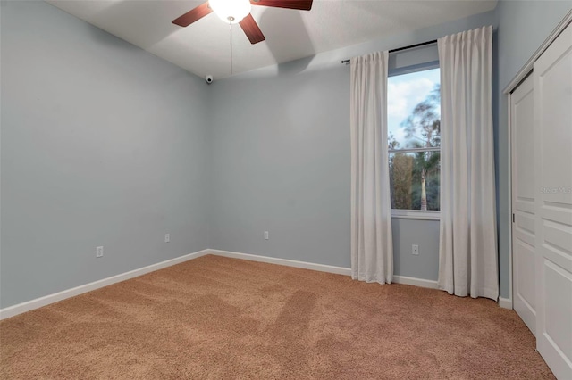 unfurnished bedroom featuring light colored carpet, a ceiling fan, and baseboards