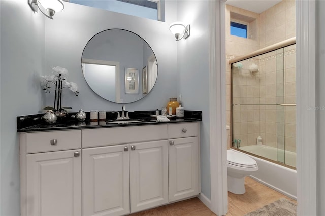 full bathroom with combined bath / shower with glass door, toilet, vanity, and wood finished floors