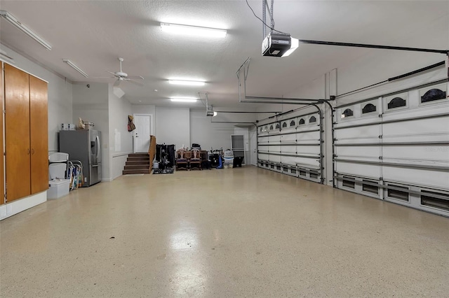 garage with a ceiling fan, a garage door opener, and stainless steel fridge