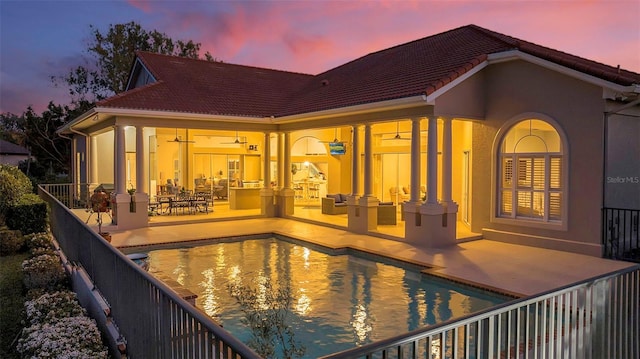 pool at dusk with a fenced in pool and a patio area