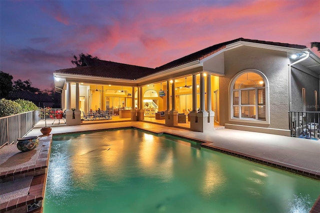 rear view of property with a patio area, stucco siding, and a fenced in pool