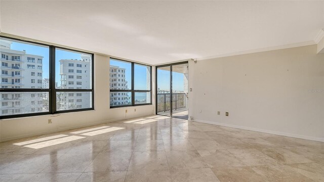 unfurnished room featuring baseboards, a city view, and crown molding