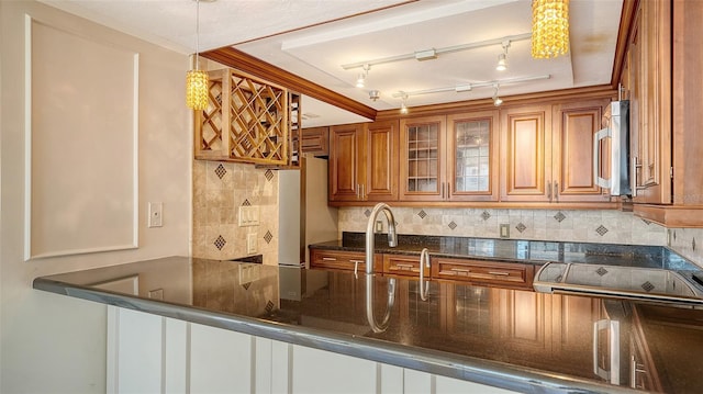 kitchen with tasteful backsplash, stainless steel microwave, brown cabinets, and freestanding refrigerator