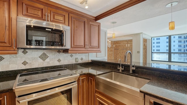 kitchen featuring a sink, brown cabinets, appliances with stainless steel finishes, and pendant lighting