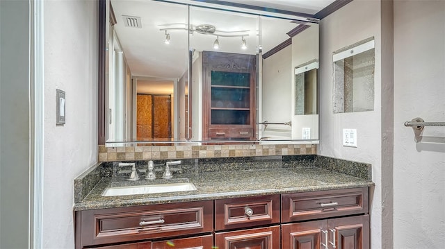 bathroom featuring vanity, visible vents, ornamental molding, a textured wall, and backsplash