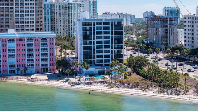 drone / aerial view featuring a city view, a view of the beach, and a water view