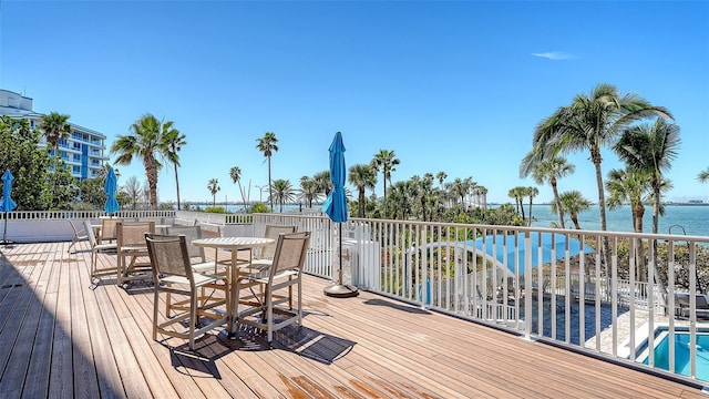 deck with outdoor dining area and a water view