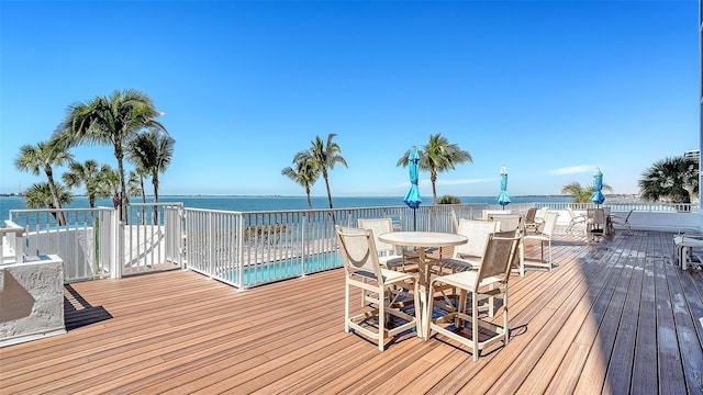 wooden terrace with outdoor dining area and a water view