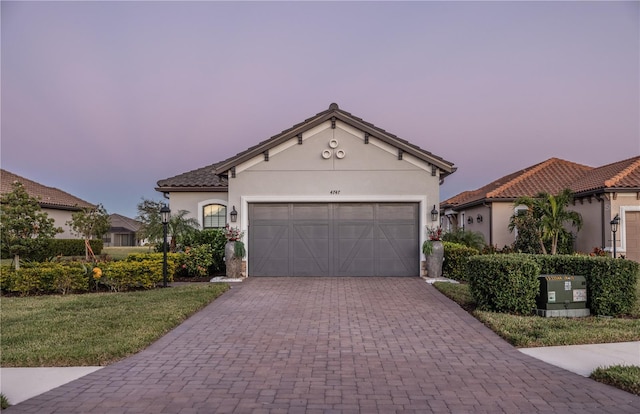 mediterranean / spanish-style home featuring stucco siding, an attached garage, driveway, and a tiled roof