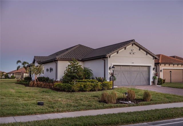 ranch-style home with an attached garage, a tiled roof, stucco siding, a yard, and driveway