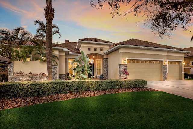 mediterranean / spanish house featuring stone siding, stucco siding, driveway, and a garage