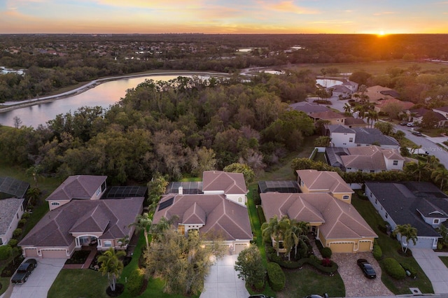 aerial view at dusk with a residential view and a water view