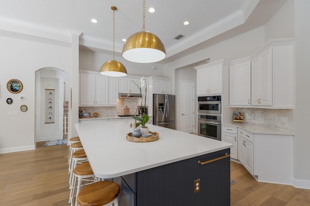 kitchen with white cabinets, appliances with stainless steel finishes, a breakfast bar area, and crown molding