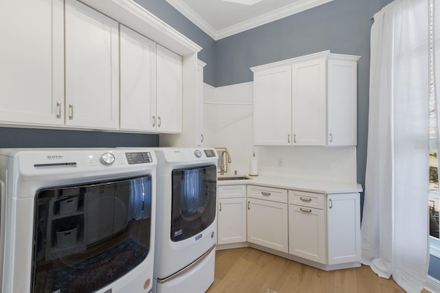 washroom featuring washing machine and clothes dryer, ornamental molding, light wood-style flooring, cabinet space, and a sink