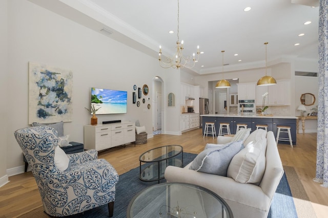 living area with baseboards, visible vents, light wood finished floors, a high ceiling, and a notable chandelier