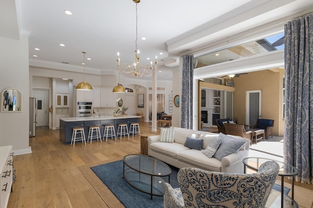 living area featuring light wood-style flooring, ornamental molding, recessed lighting, baseboards, and a chandelier