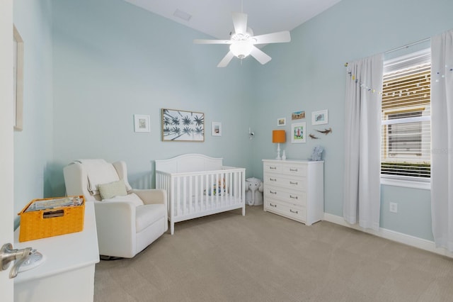 bedroom with light colored carpet, a crib, baseboards, and multiple windows