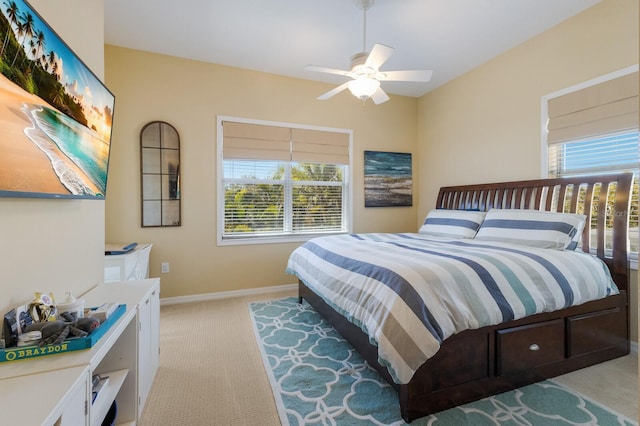 bedroom with a ceiling fan, multiple windows, light colored carpet, and baseboards