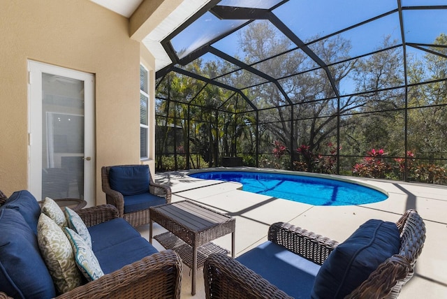 pool featuring an outdoor living space, glass enclosure, and a patio area