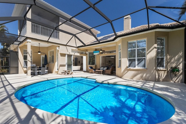 outdoor pool with a patio area, glass enclosure, and a ceiling fan