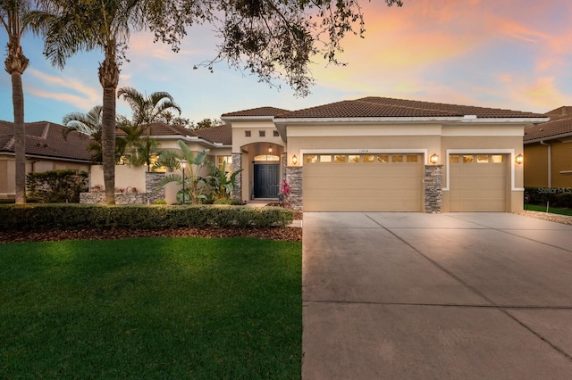 mediterranean / spanish-style house with a tile roof, concrete driveway, stucco siding, a lawn, and a garage