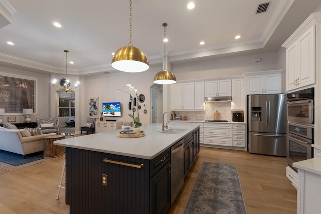 kitchen featuring visible vents, a sink, white cabinets, under cabinet range hood, and appliances with stainless steel finishes