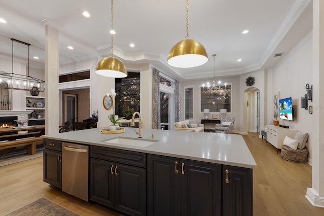 kitchen featuring a warm lit fireplace, a sink, light countertops, stainless steel dishwasher, and open floor plan