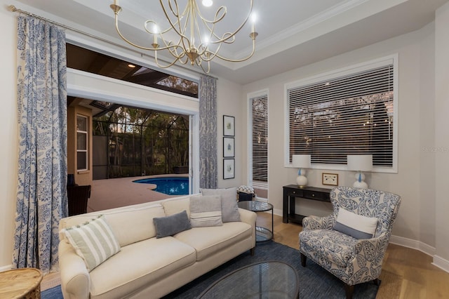 living room featuring a chandelier, crown molding, a raised ceiling, and baseboards