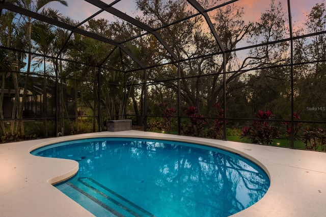 outdoor pool with glass enclosure and a patio