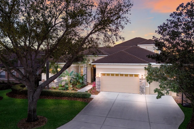 view of front of home with stucco siding, a tile roof, a yard, concrete driveway, and an attached garage