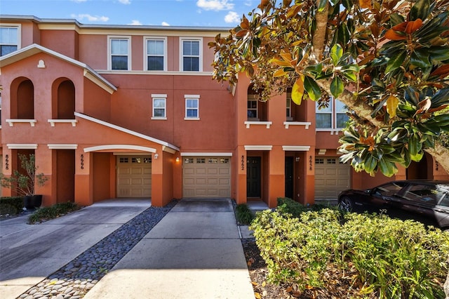 view of property with an attached garage, driveway, and stucco siding