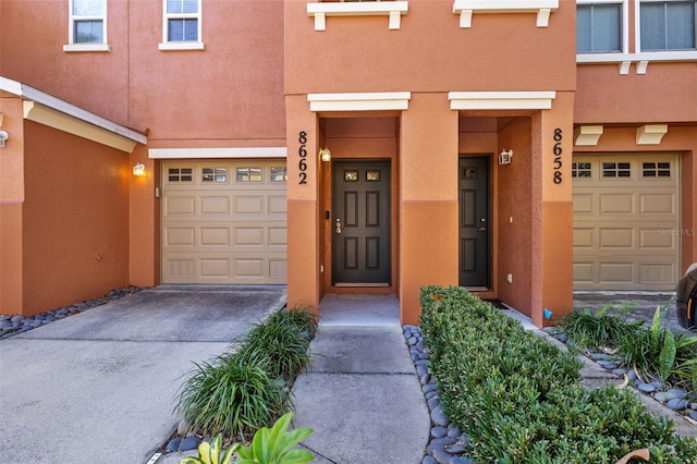 property entrance featuring stucco siding, driveway, and a garage