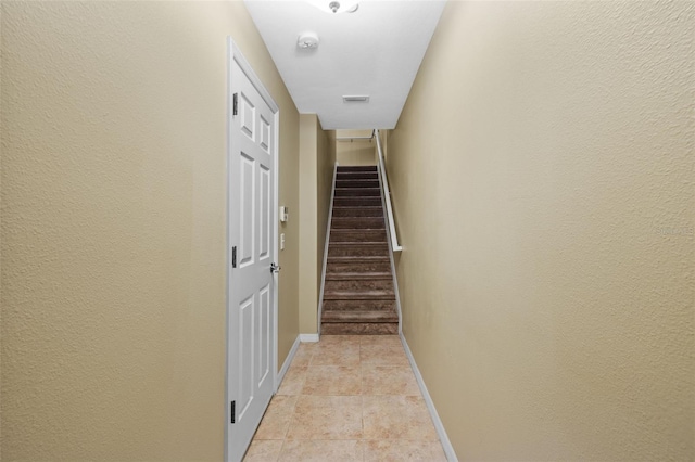 hallway with visible vents, baseboards, light tile patterned flooring, and stairs