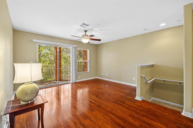 interior space with visible vents, baseboards, an upstairs landing, wood finished floors, and a ceiling fan