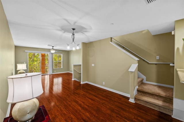 unfurnished living room featuring stairs, wood finished floors, baseboards, and ceiling fan