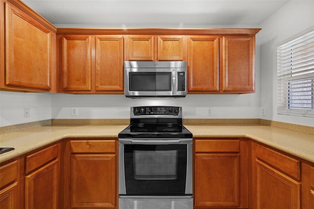 kitchen featuring stainless steel appliances, brown cabinets, and light countertops