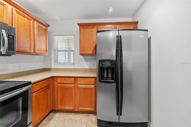 kitchen featuring brown cabinetry, appliances with stainless steel finishes, and light countertops