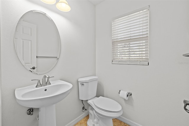 half bathroom with a sink, baseboards, and toilet