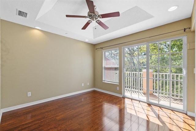 spare room with visible vents, baseboards, a tray ceiling, recessed lighting, and wood finished floors