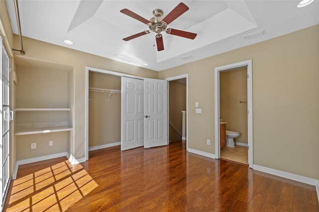 unfurnished bedroom featuring wood finished floors, visible vents, a closet, and baseboards