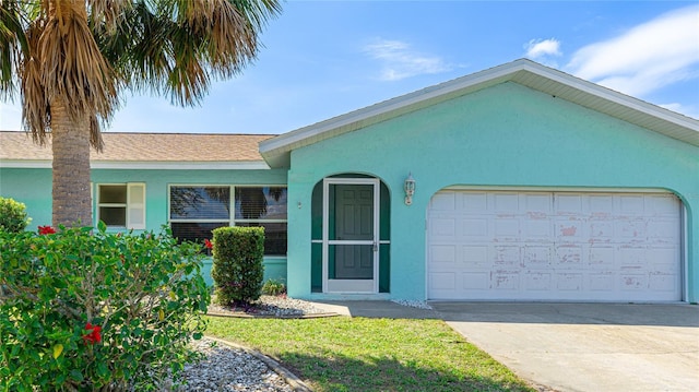 ranch-style home with stucco siding, an attached garage, roof with shingles, and driveway