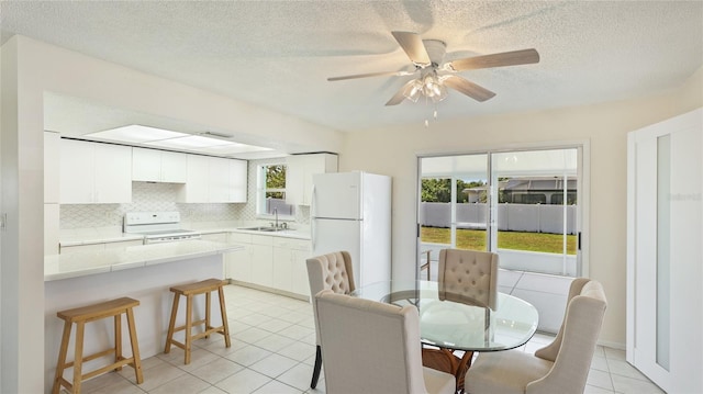 dining area featuring a textured ceiling, light tile patterned flooring, and ceiling fan